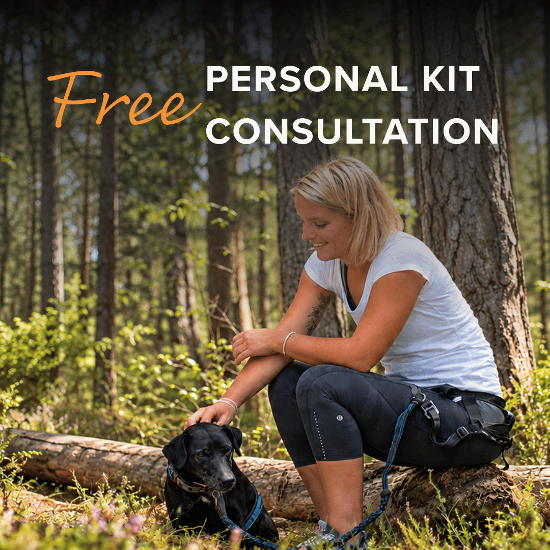 A woman in a white t-shirt and dark leggings sits on a log in a forest, petting a black dog. Large text overlays read 'Free PERSONAL KIT CONSULTATION'.